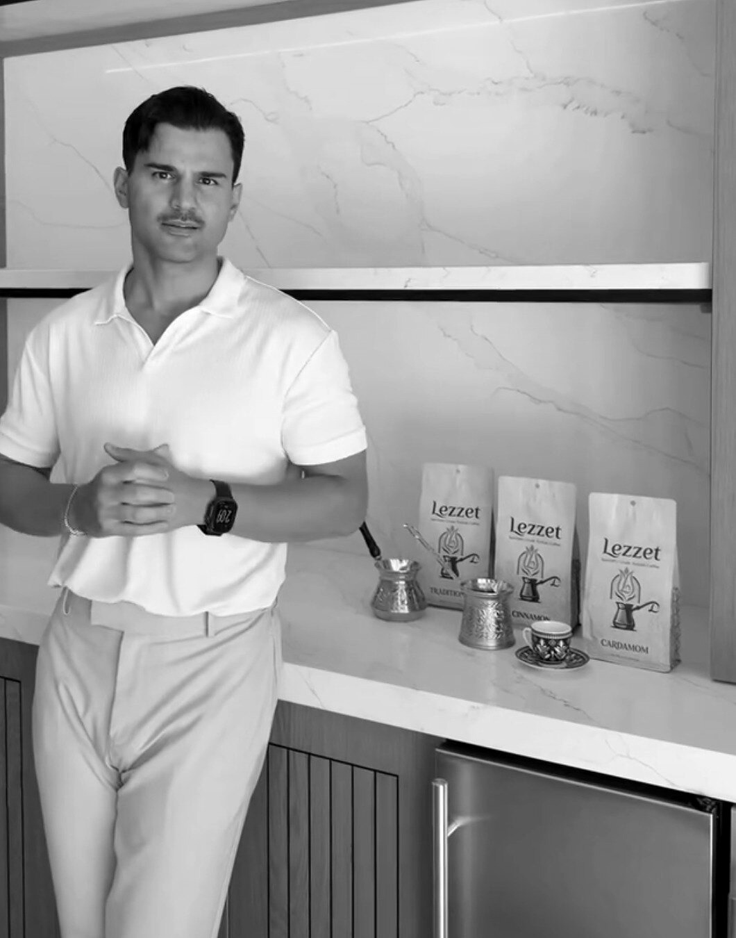 Muhammed Çam standing beside Lezzet Turkish coffee bags, a cezve, and a Turkish coffee cup.