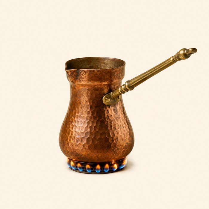 A copper cezve warming over a low flame
