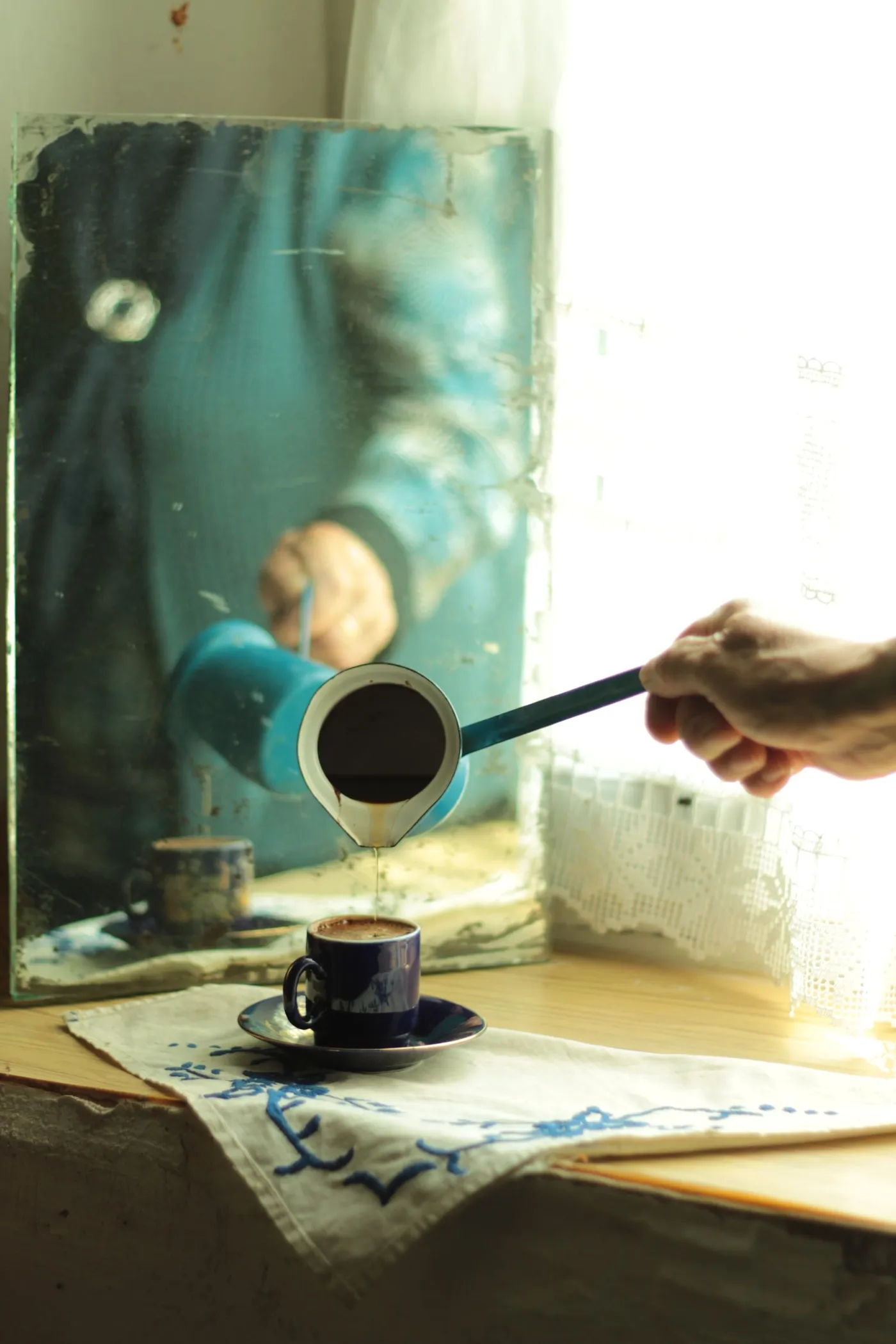 Turkish coffee poured into a cup by a sunlit window