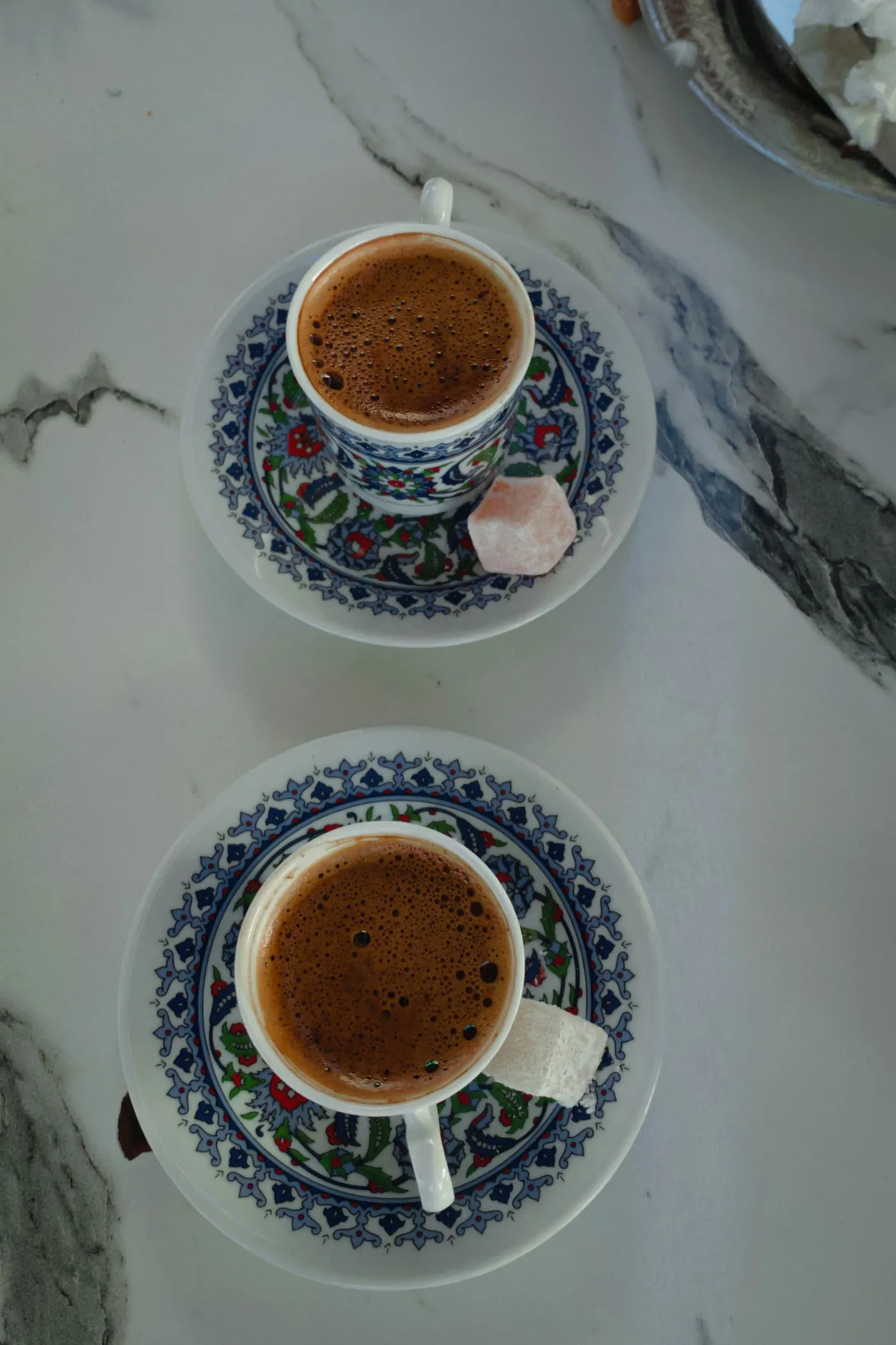 Two ornate cups of Turkish coffee with lokum, seen from above