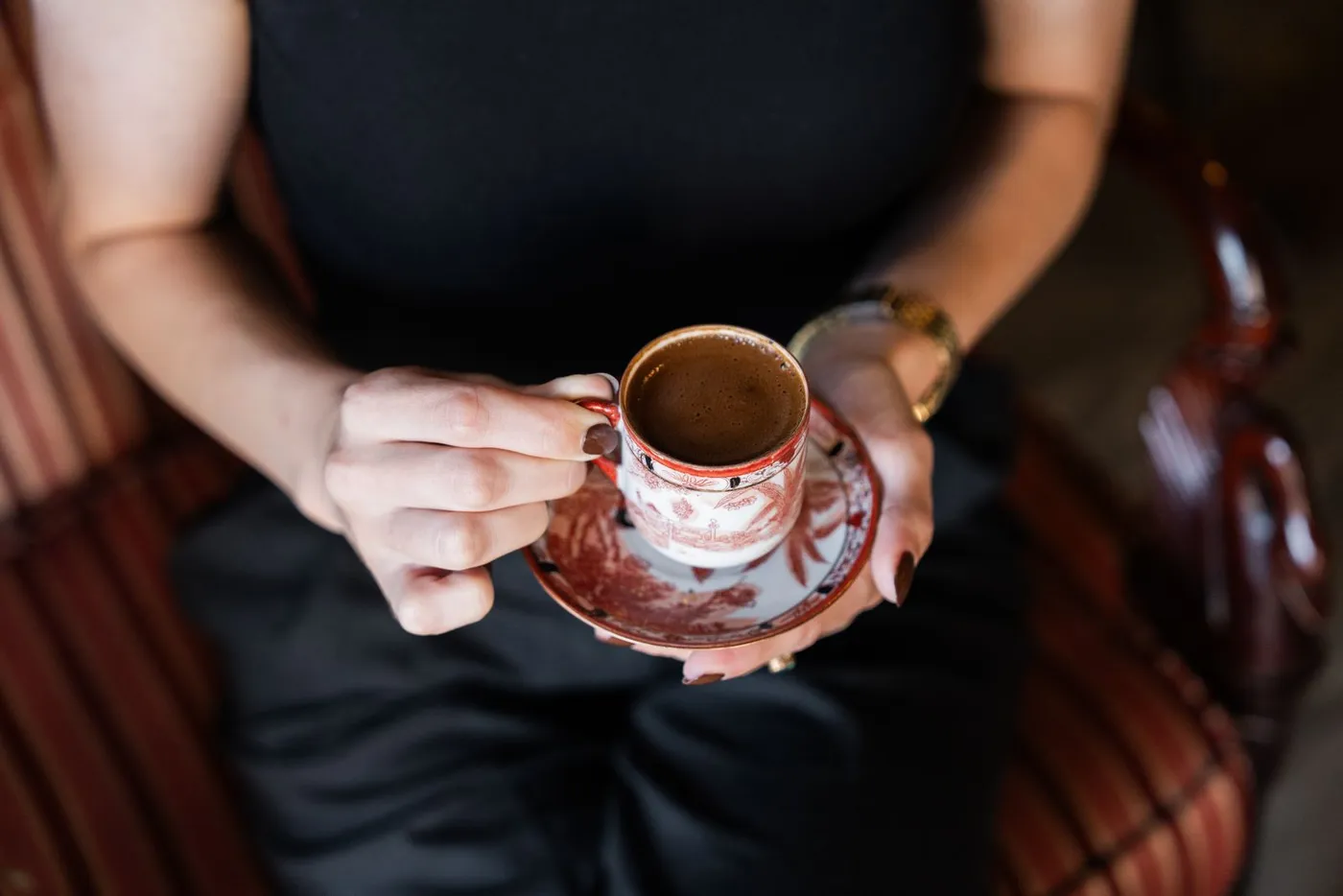 A woman holding a small ornate cup of Turkish coffee